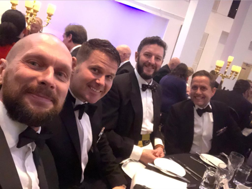 Selfie of four men in black tie dress at a dinner table.