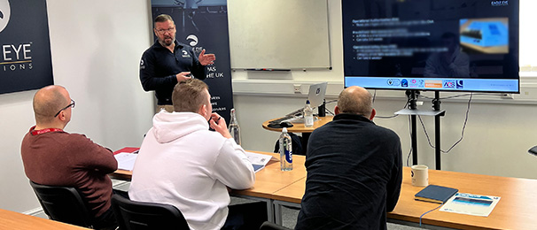 Image of people in a classroom being taught drone theory by a man in an Eagle Eye Innovations branded jumper.