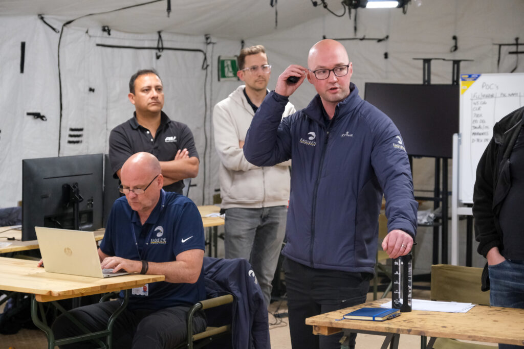Man in a field flying a drone towards the camera.