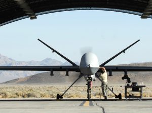 Image of Reaper in an outdoor hangar with a man performing repairs.