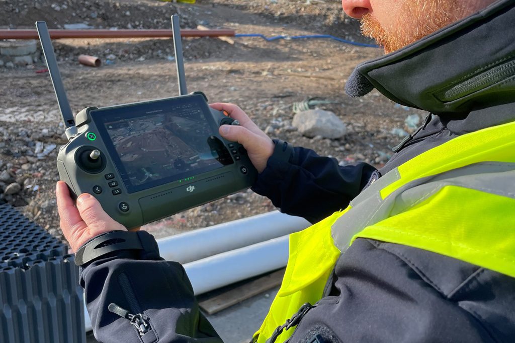 Close up of drone controller screen. Man using it on construction site.
