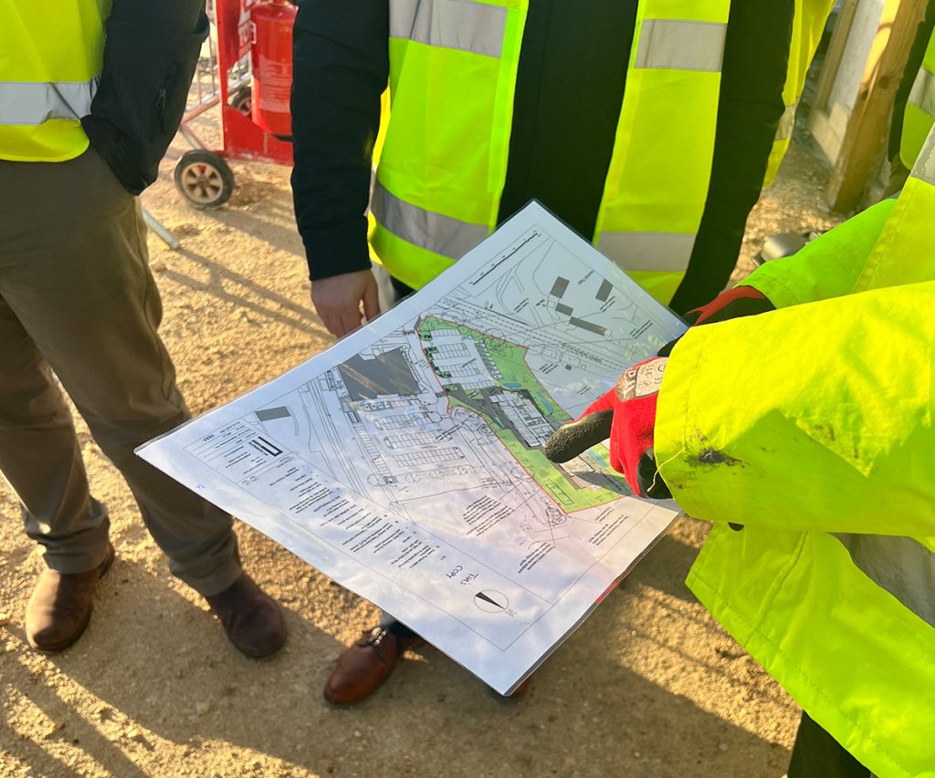 A group of people standing and using a construction map to plan a drone flight route.