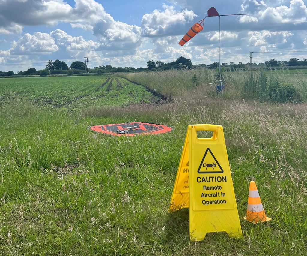 Safety sign in field in front of a drone landing pad.